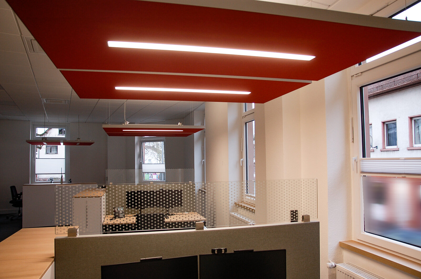 Rotes Deckensegel mit integrierten LED-Lichtlinien im Büro